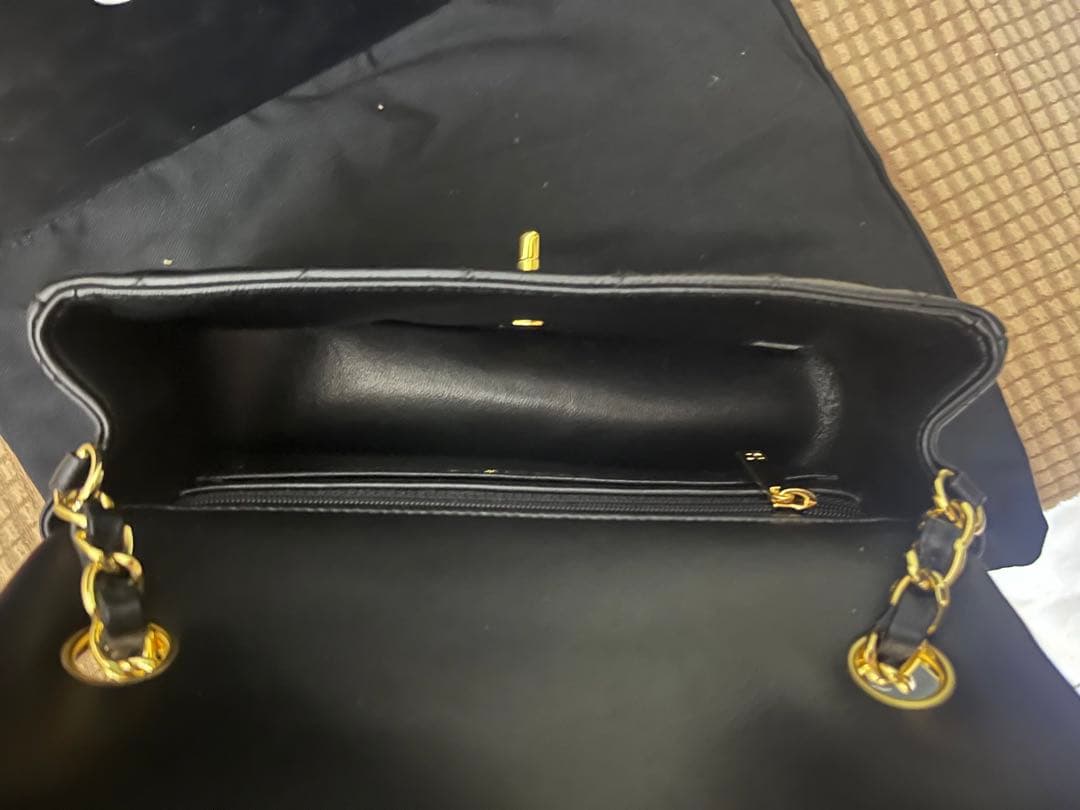 キルティングデザインのブラックレザーショルダーバッグ、ゴールド金具付き。