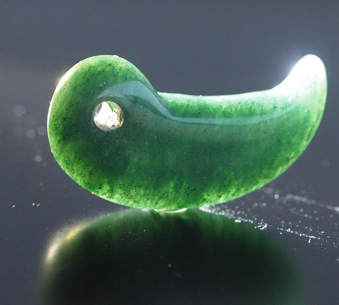 光にかざすと薄緑の細い帯状紋が出現、頭・胴の間には沈線、ずんぐり形の勾玉　沖縄の